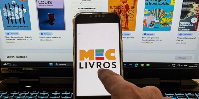 Phone screen displaying the MEC LIVROS logo, held in front of a laptop with book covers on screen; a finger points at the logo.