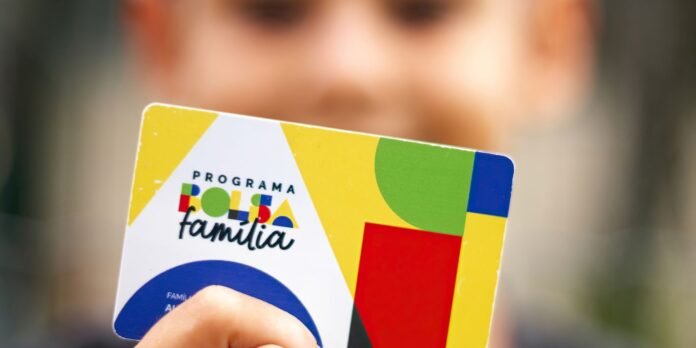 Colorful program card titled 'Programa Folha familia' held by a person, close to the camera.