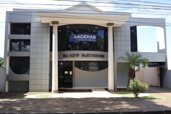 Front view of a modern office building with two tall columns and a curved entrance, showing signage for AGEHAB Agência de Habitação and Ed. New Parthenon