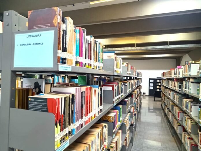 Library aisle with tall metal shelves filled with colorful books, labeled Literature in the foreground.