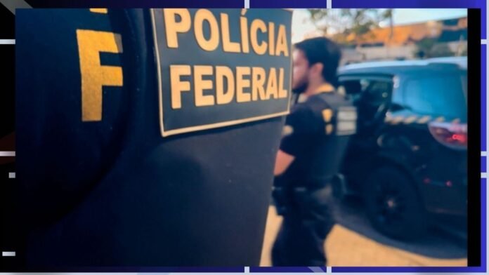 Close-up of a Polícia Federal patch on a dark uniform, with officers and a patrol vehicle in the background at a street scene.