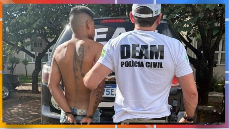 Officer from DEAM Polícia Civil stands beside a shirtless man with a large back tattoo near a police SUV, facing away from camera.