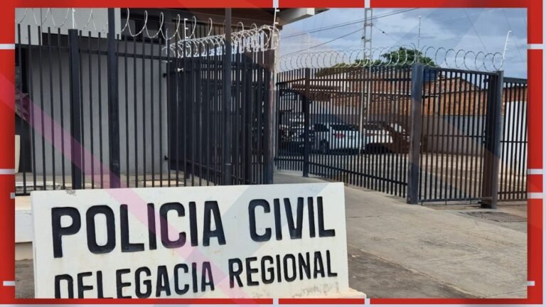 Sign reading 'POLICIA CIVIL DELEGACIA REGIONAL' in front of a tall barbed-wire security fence and gate; a parking area with a white car visible behind.