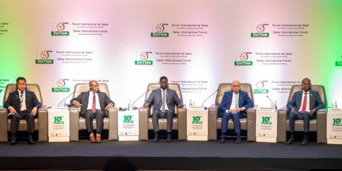 Five men in suits sit in armchairs on a stage for a conference, with a Dakar International Forum backdrop behind them.
