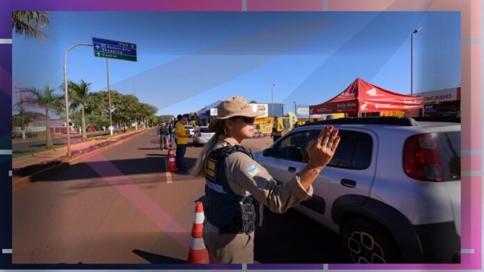 Uniformed officer directs traffic with hands up at a road checkpoint, a white car stopped nearby and orange traffic cones visible.