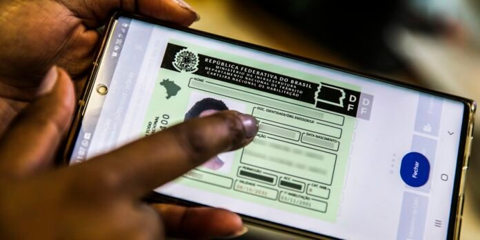 Close-up of a hand holding a smartphone displaying a Brazilian CNH driver's license on the screen