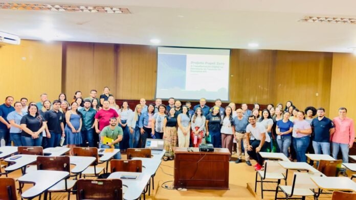 Large group of people posing for a photo in a classroom with desks and a projector screen behind them
