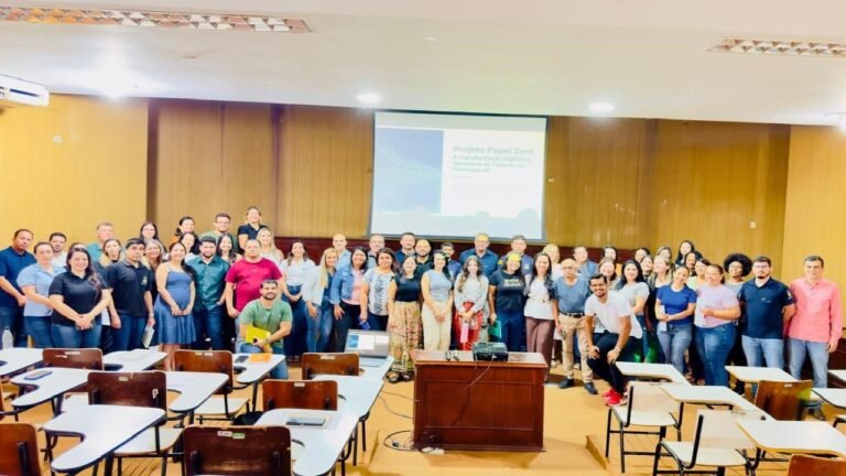 Large group of people posing for a photo in a classroom with desks and a projector screen behind them