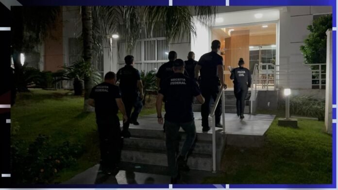 Uniformed officers from Receita Federal and Polícia Civil walk up stairs to a lit building entrance at night. (Raid scene)