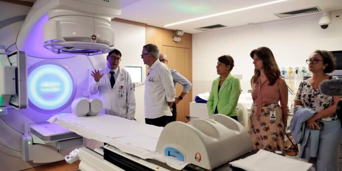Medical team explains a Versa HD radiotherapy machine to visitors in a hospital treatment room.