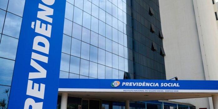 Modern blue sign for Previdência Social on a glass-front government building facade