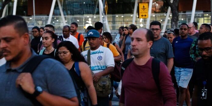 Crowd of diverse pedestrians walking together on a city street at dusk.
