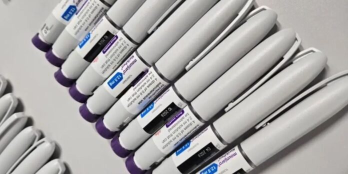 Row of white laboratory test tubes with purple caps, arranged diagonally with visible labels, on a lab surface.