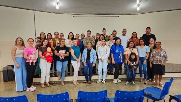 Diverse group of adults and children posing on a small stage in a hall for a group photo.