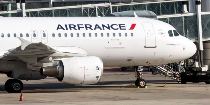 Air France Airbus A320 at the gate with jet bridge attached, engine clear in foreground and nose pointing right