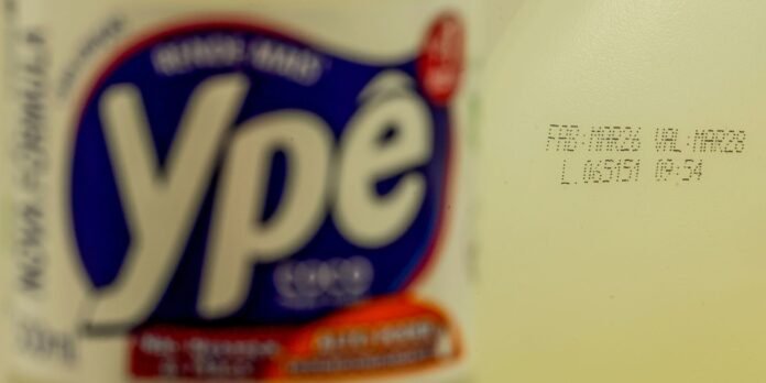 Blurred close-up of a yogurt bottle label with a bold blue circular logo on the left and a stamped production date on the right.