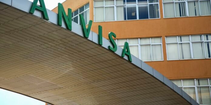 Green 'ANVISA' signage on a white entry canopy of a tan-orange building, indicating the entrance area.