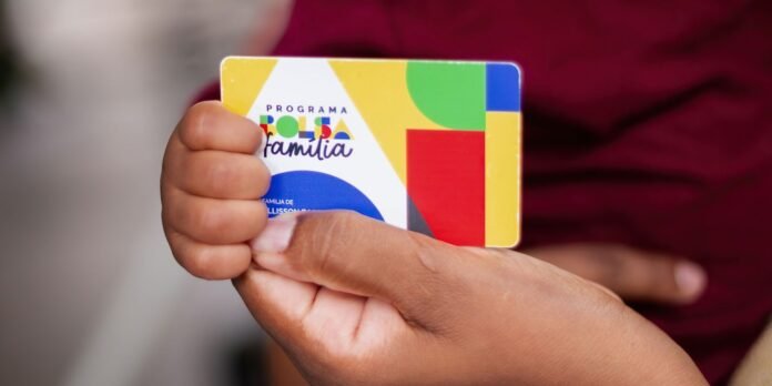 Hand holding a colorful geometric card labeled 'Programa Familia' against a blurred background (focused on the card)