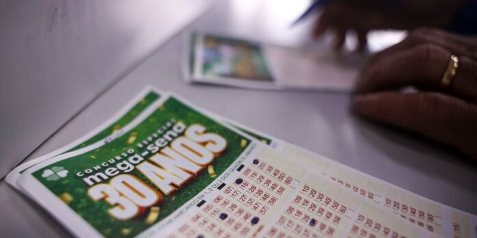 Close-up of green lottery scratch-off tickets on a table, with a hand wearing a gold ring in the background.