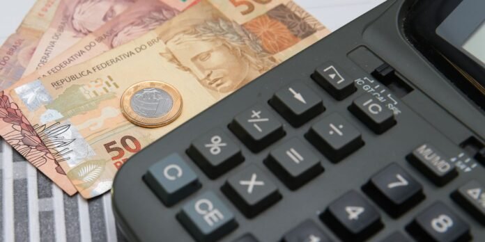 Brazilian 50 real banknotes with a calculator nearby, implying financial calculation or budgeting in Brazil