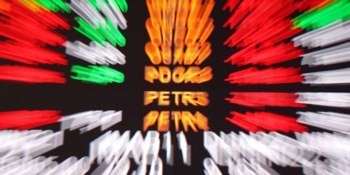 Blurred stock market ticker with red, green, and white price bars and orange center text indicating names or values.