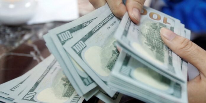 Close-up of hands counting a fan of US $100 bills, stacked in multiple bundles