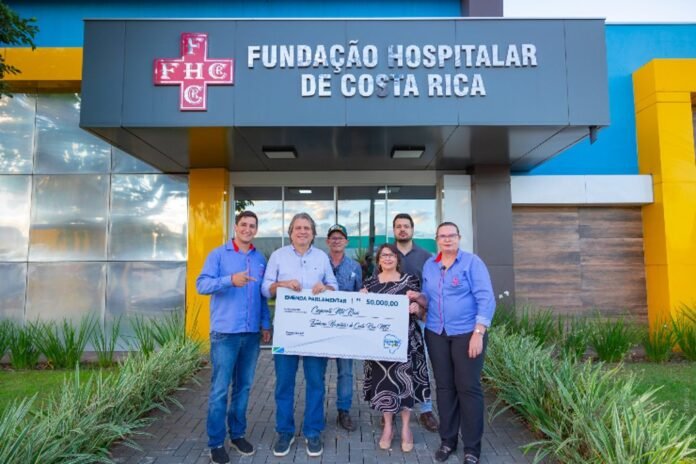 Six people stand outside Fundação Hospitalar de Costa Rica, holding a large donation check together as a presentation.