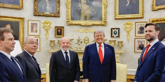 Five men in dark suits pose for a photo in a gold-accented room with ornate frames and portraits on the walls in the background.