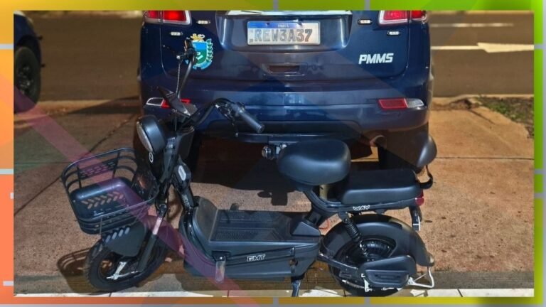 Black scooter with a front cargo basket parked in front of a blue SUV; license plate is visible on the car behind.