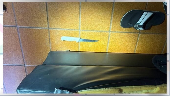 White-handled knife on brown tiled floor beside a black bench; a sneaker is visible in the top-right corner.