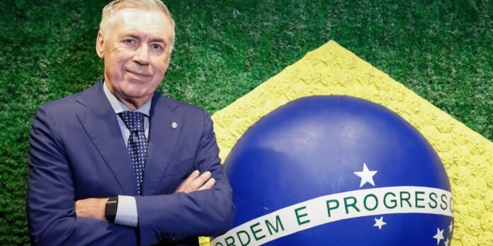 Man in a navy suit with arms crossed standing beside a large Brazil flag-themed display (blue ball with 'Ordem e Progresso') against a green hedge backdrop.