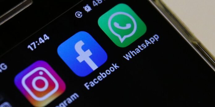 Close-up of a smartphone home screen with Instagram, Facebook, and WhatsApp icons visible in a row on a dark background.