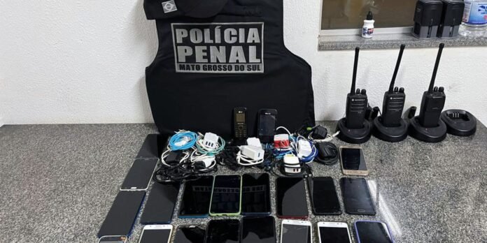 Evidence display: multiple mobile phones, chargers, cables, and two-way radios arranged on a countertop with a Penal Police vest in the background.