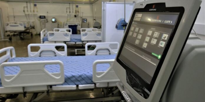 ICU ward with empty hospital beds and medical monitors in the background.