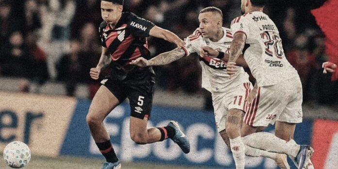 Soccer players in black and white kits scramble for the ball during a match, with a dancer in black leading the run.