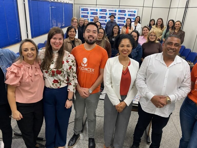 Diverse group of colleagues posing for a group photo in a conference room with SEMED banners in the background.