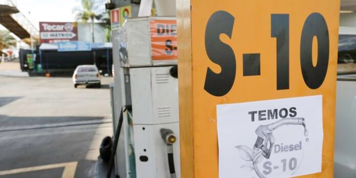 Close-up of an orange S-10 fuel sign with a white poster saying TEMOS Diesel S-10 attached to the pump in the foreground