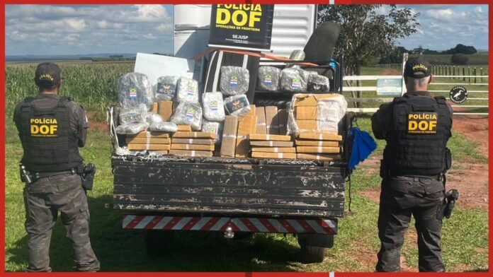 Two Polícia DOF officers stand on either side of a pickup truck loaded with wrapped packages and cardboard boxes filled with seized goods behind them in an open rural area.