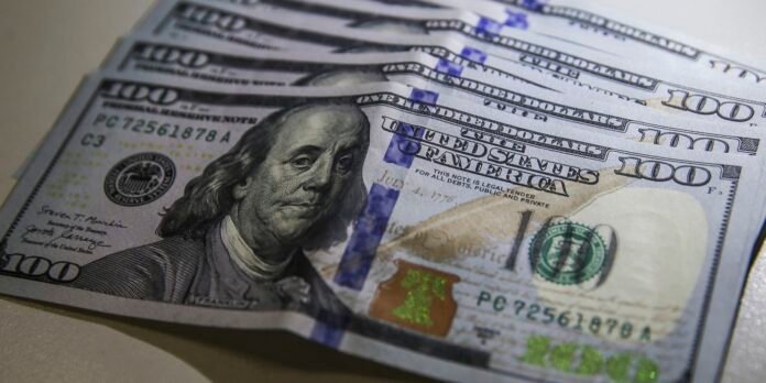 Close-up of several fanned hundred-dollar bills featuring Benjamin Franklin in portrait.