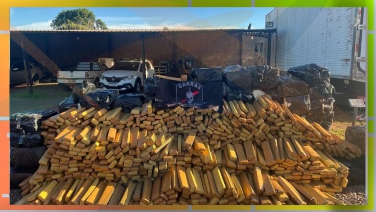 Large pile of gold bars stacked outdoors under a carport, with black bags behind and a banner with a logo in front.