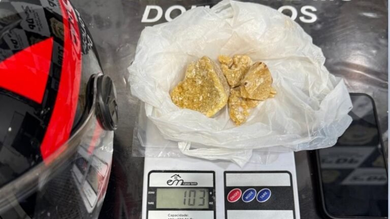 Brown chunky substance in a plastic bag resting on a digital kitchen scale showing 103 g