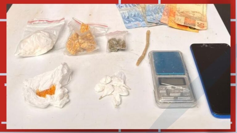 Assorted drug paraphernalia on a table: baggies with white powder, pills, a small scale, cash, and a phone.