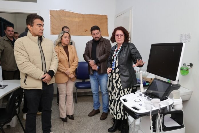 Clinician explains ultrasound machine to a small group of visitors in a clinical room to assess equipment use.