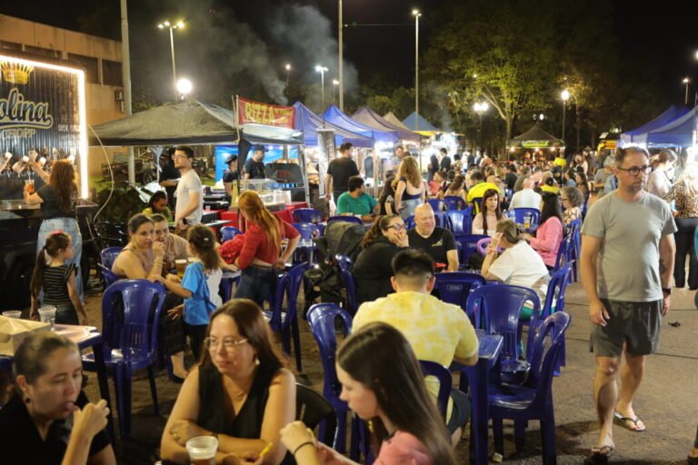 Night market at night: people sit at blue plastic tables under string lights with food stalls in the background.