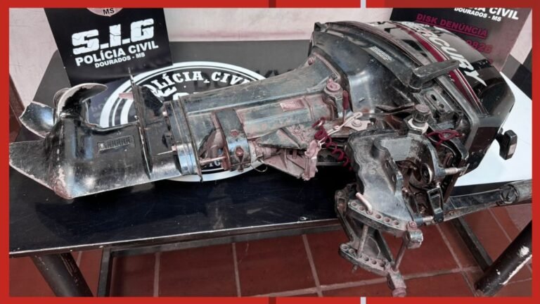 Damaged outboard boat motor on a table, with a Polícia Civil banner in the background