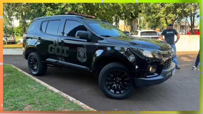 Black police SUV parked on a street with trees, features a crest and 'GOT' lettering on the side, a man stands nearby in casual clothing.