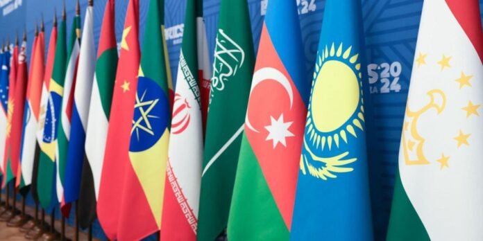 Row of colorful national flags lined up in a formal setting, likely at an international summit or conference.