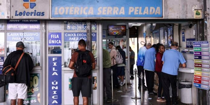 People stand in line inside a Brazilian lottery house, with blue signs and ticket windows along the walls.