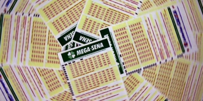 Pile of yellow Mega-Sena lottery tickets scattered and fanned out, showing printed numbers