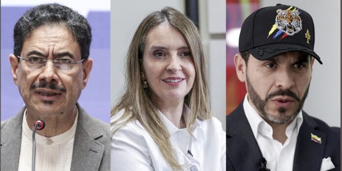 Three people in a panel: left is a middle-aged man with glasses speaking into a microphone, center a smiling woman in a white blouse, right a man wearing a black cap with a tiger design.